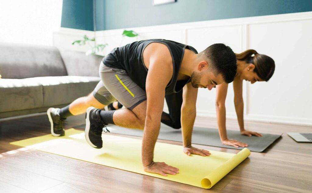 Man and woman working out in hotel room on yoga mats: quick workouts