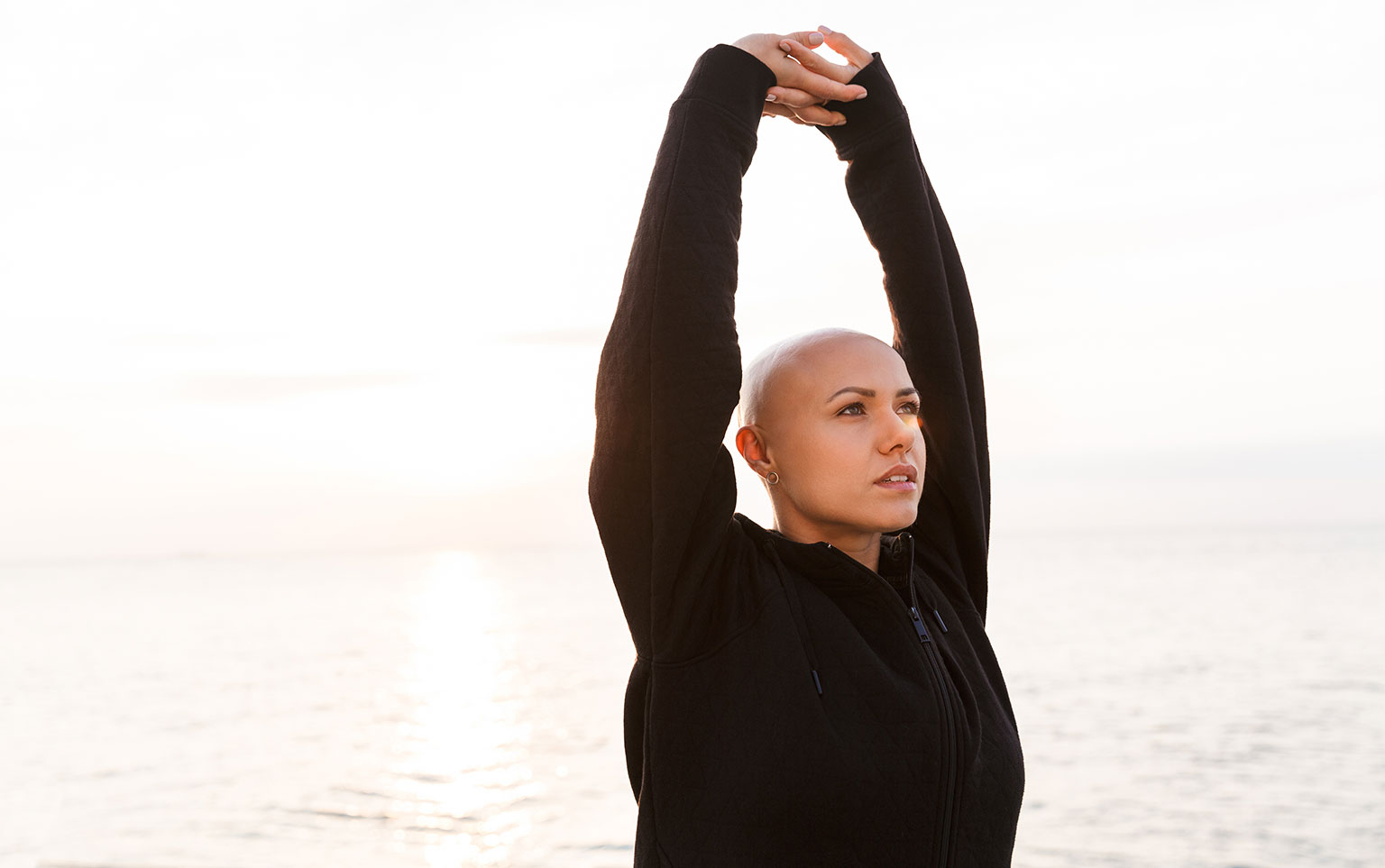 Bald woman doing yoga outdoors for a blog about cancer awareness