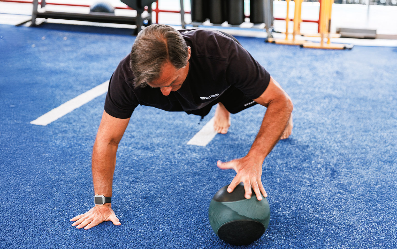 middle aged man doing workout on gym turf for a blog about the benefits of strength training for older adults