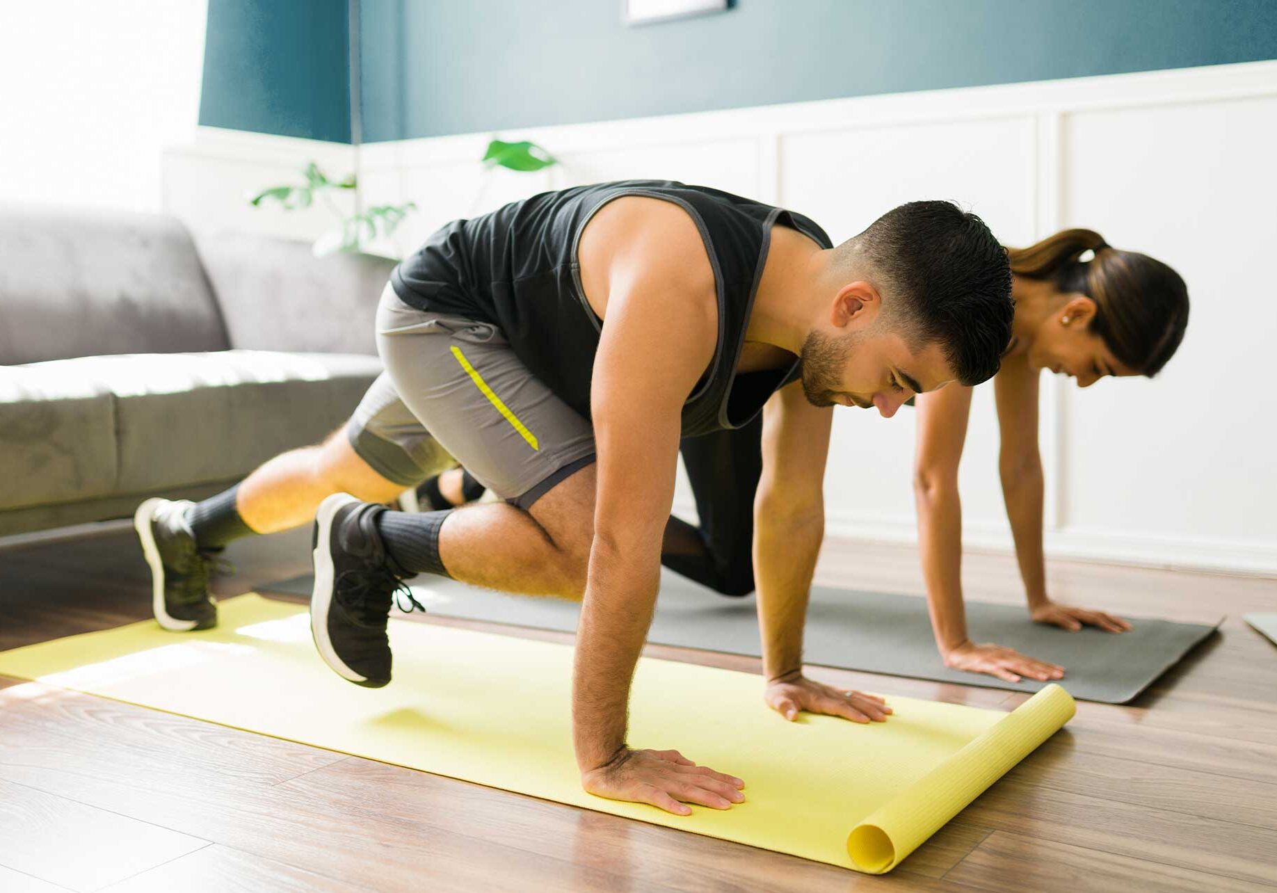 Man and woman working out in hotel room on yoga mats: quick workouts