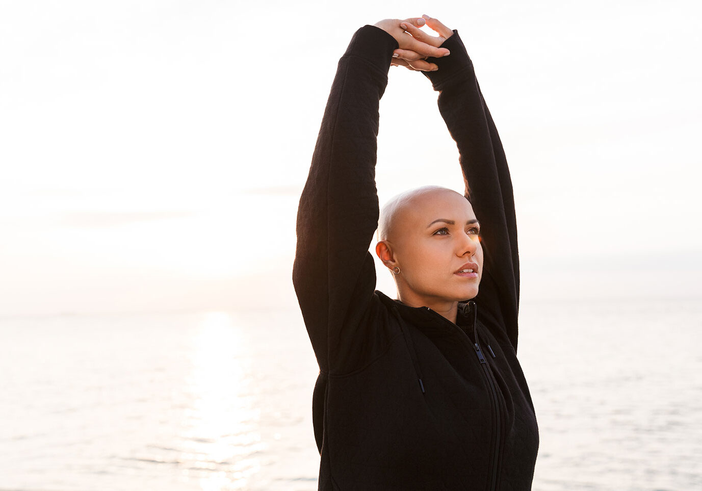 Bald woman doing yoga outdoors for a blog about cancer awareness