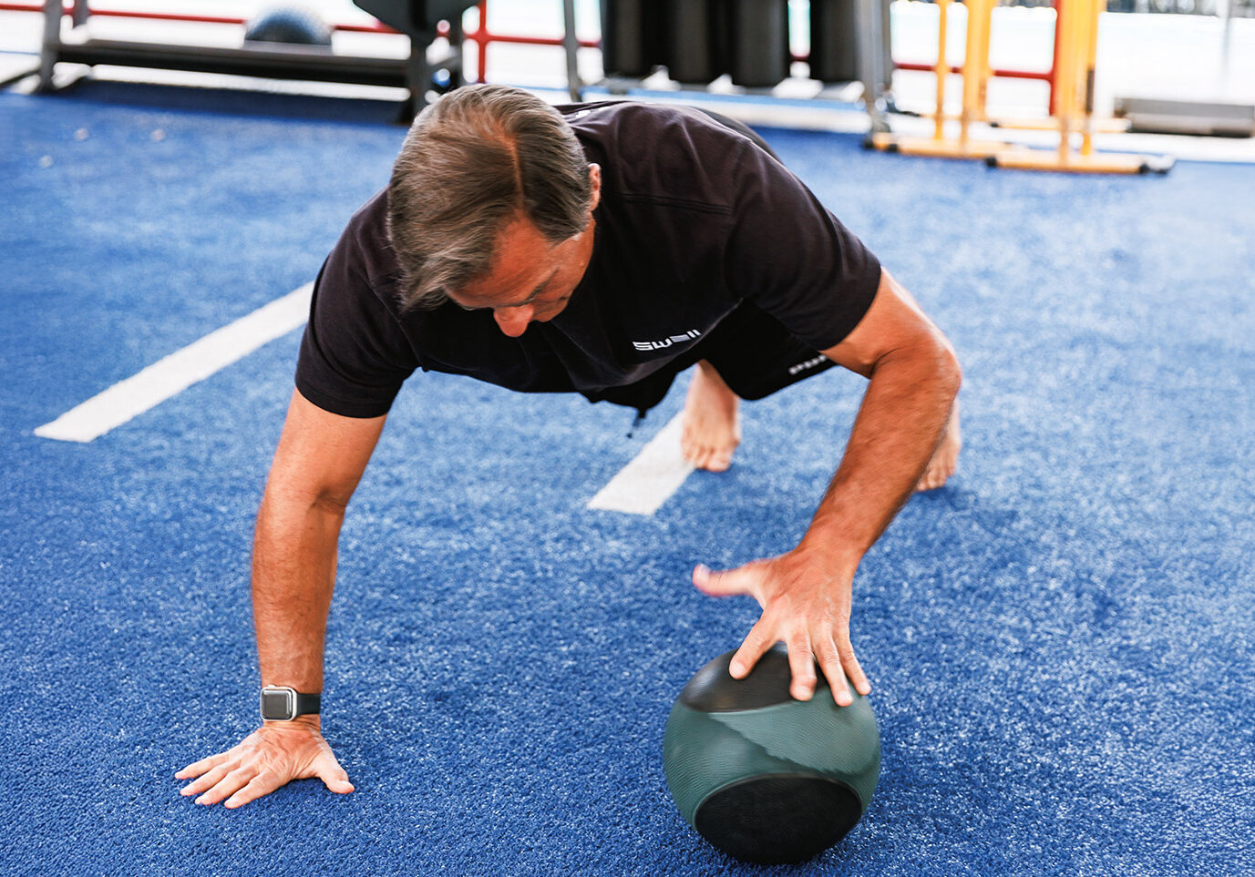 middle aged man doing workout on gym turf for a blog about the benefits of strength training for older adults