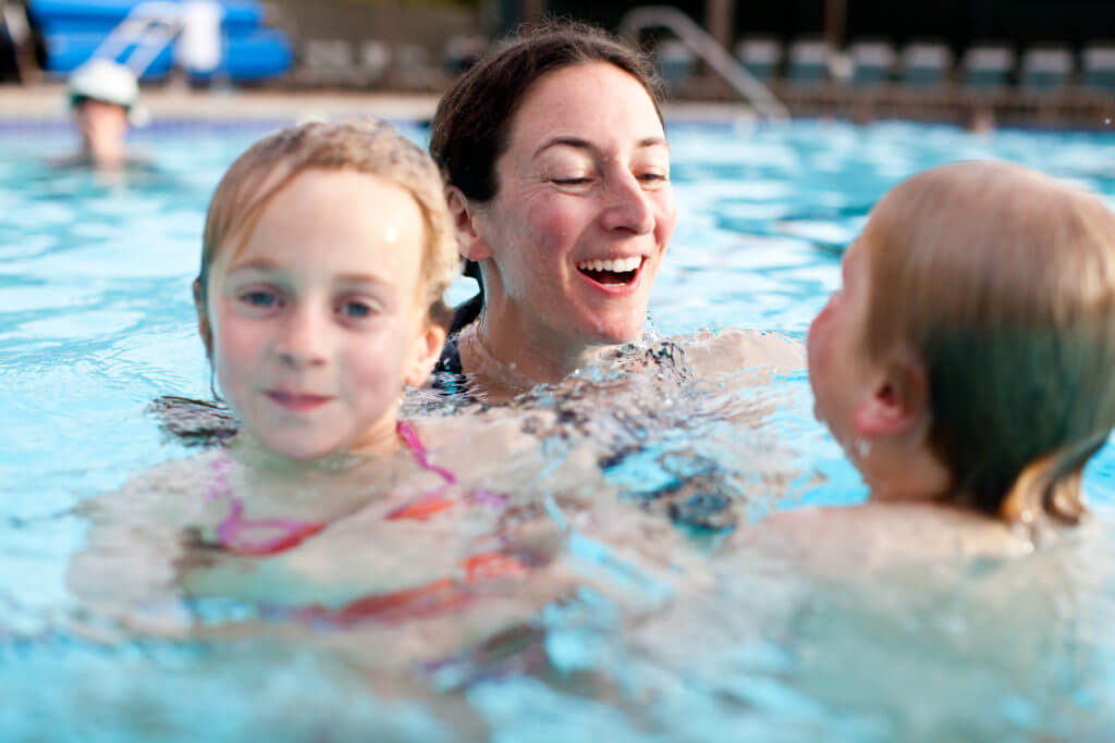Mother holding two children in pool