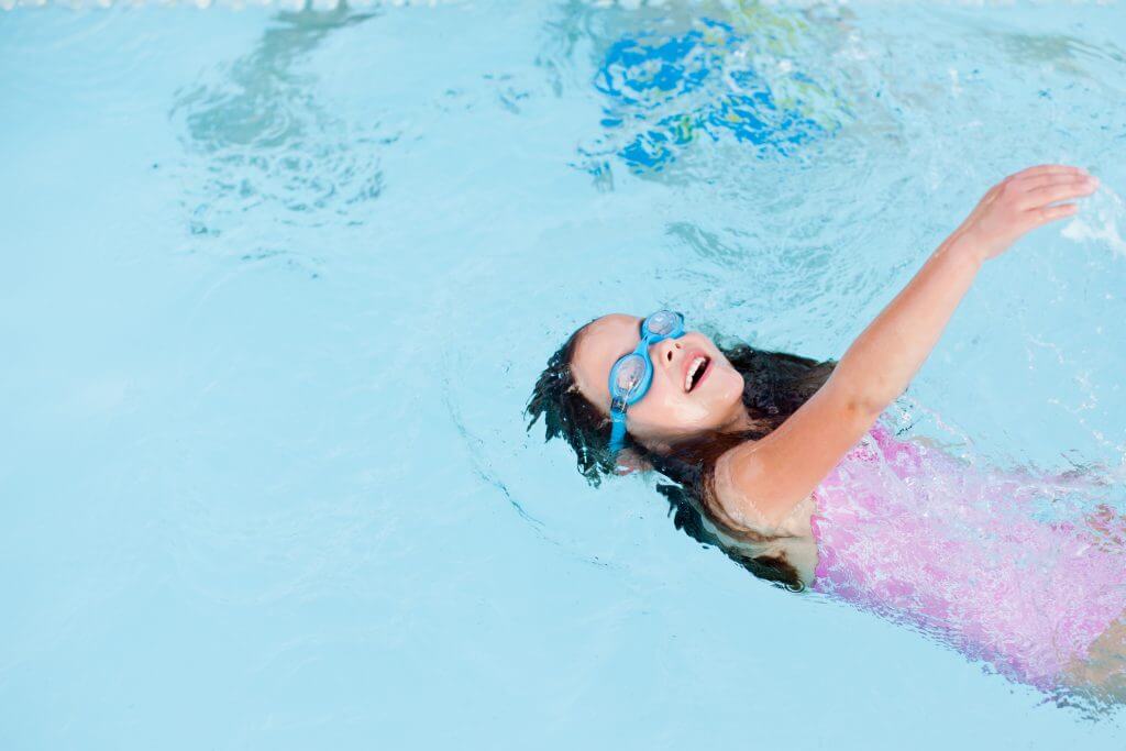 Young girl swimming backstroke in lap pool