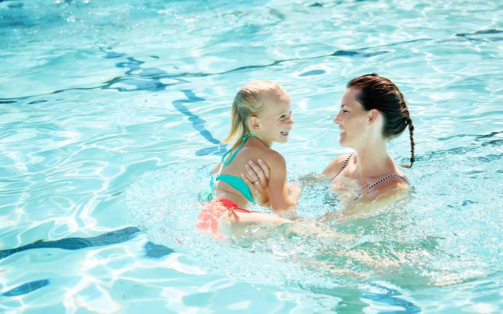 mother and daughter enjoying an outdoor fitness class in the pool