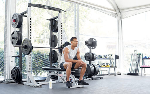 man resting between the workout sets of his favorite types of workouts, weightlifting and strength training